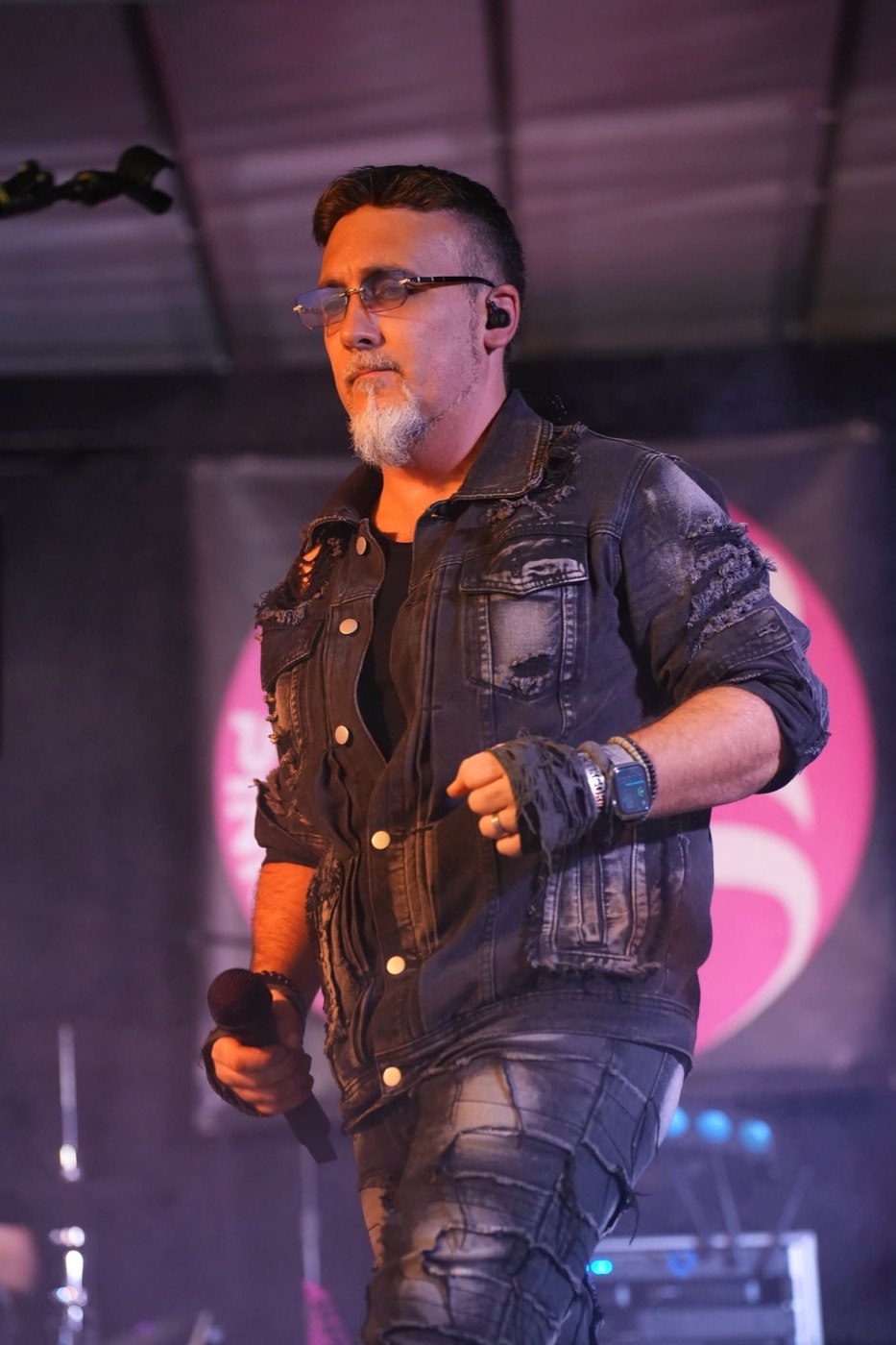 Chanteur de PINK GORILLA, micro à la main, devant le décor rose du groupe.