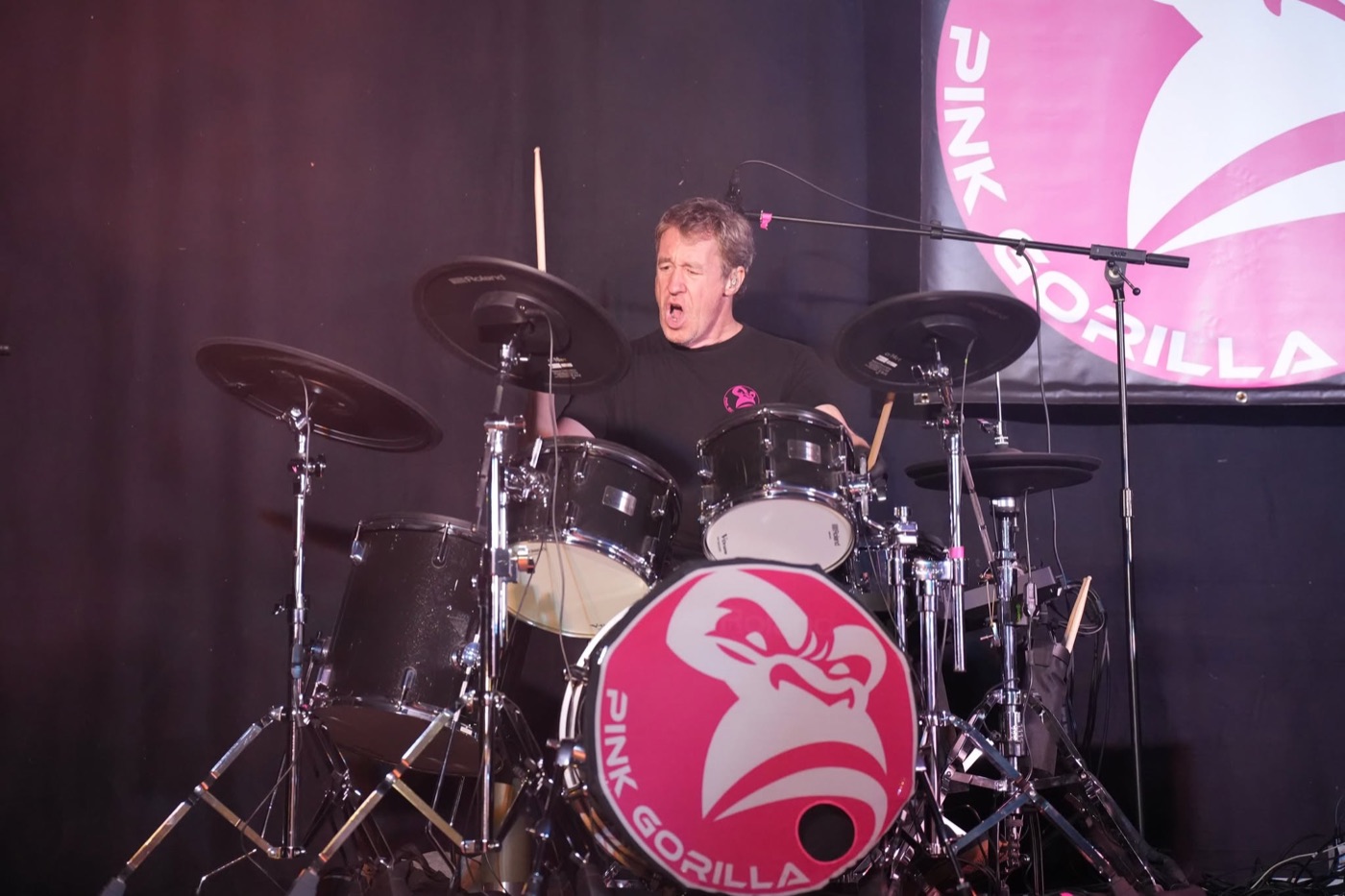 Batteur de PINK GORILLA jouant derrière sa batterie et le logo rose de la grosse caisse.