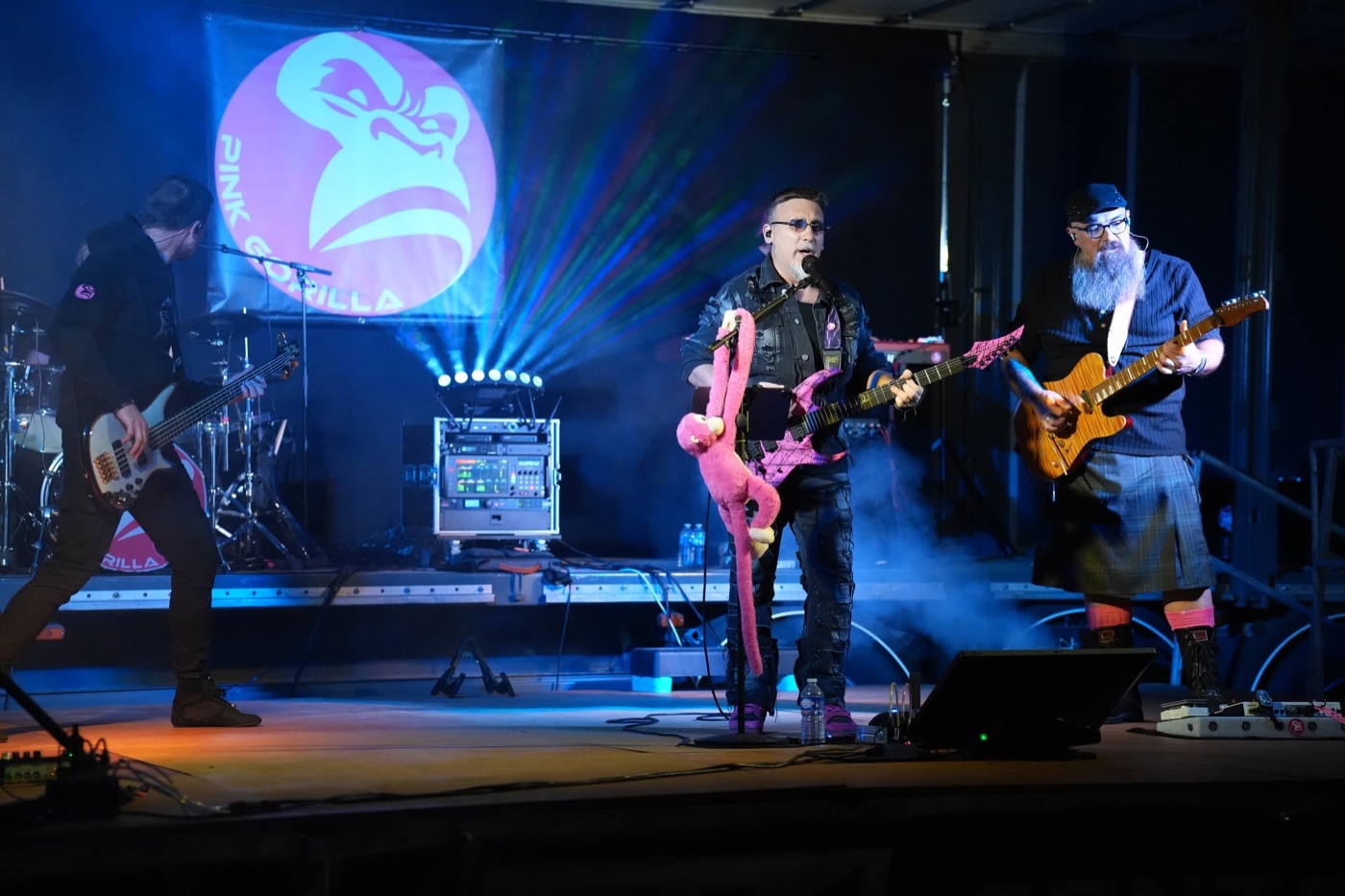 Chanteur, guitariste et bassiste de PINK GORILLA sur scène dans des faisceaux de lumière bleue.