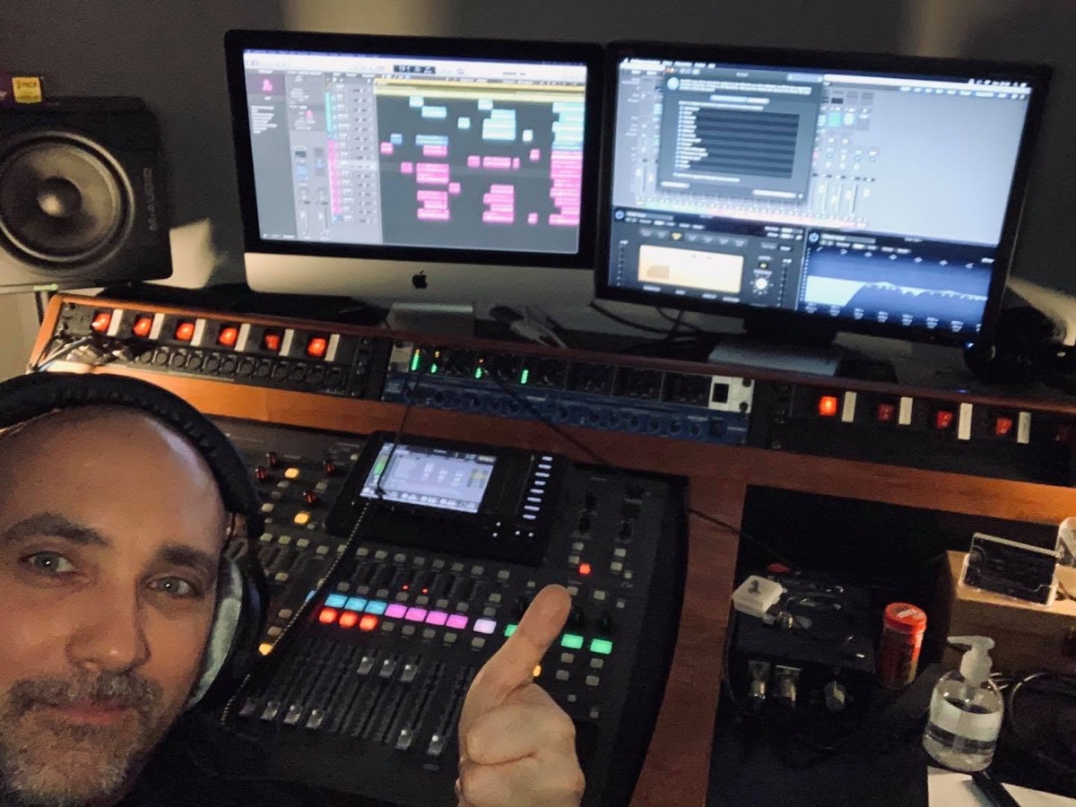 Fabio devant une console de mixage et deux écrans dans une régie audio.